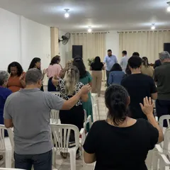 Igreja de pé no fim do culto, com mãos levantadas em oração
